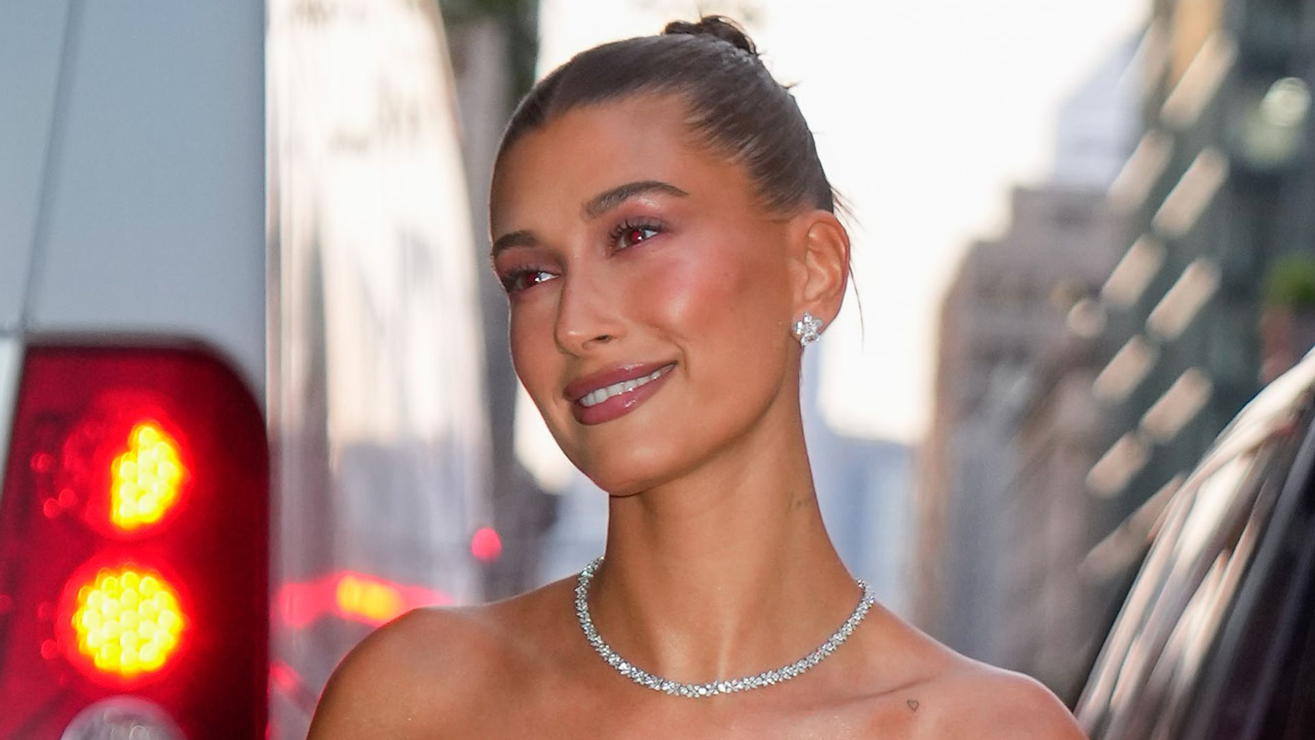 Hailey Bieber smiling in a pink dress in New York