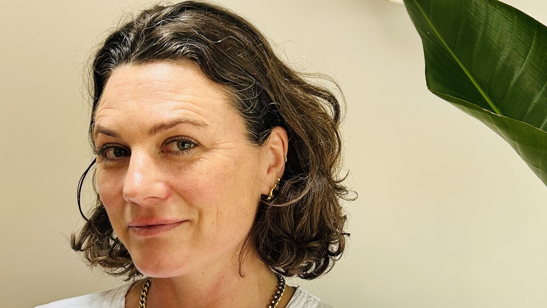 Woman in a white top next to a plant
