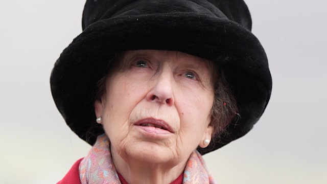 Princess Anne wearing red coat, black hat and pearls