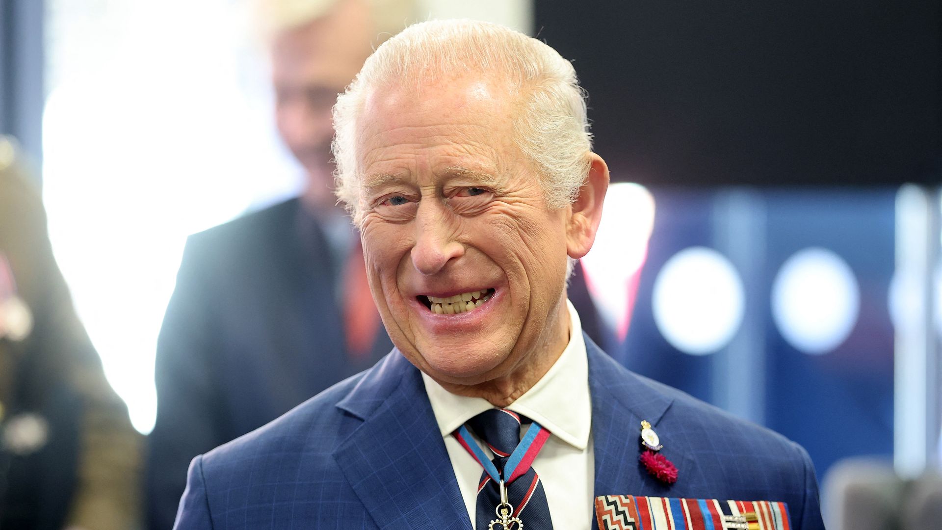 King Charles grinning with medals on blazer