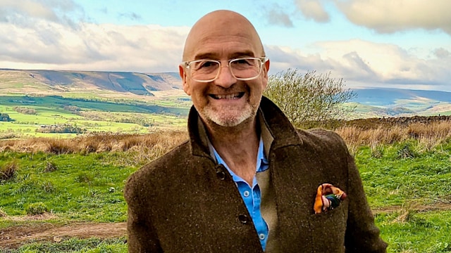 David Harper standing in a field in a brown jacket