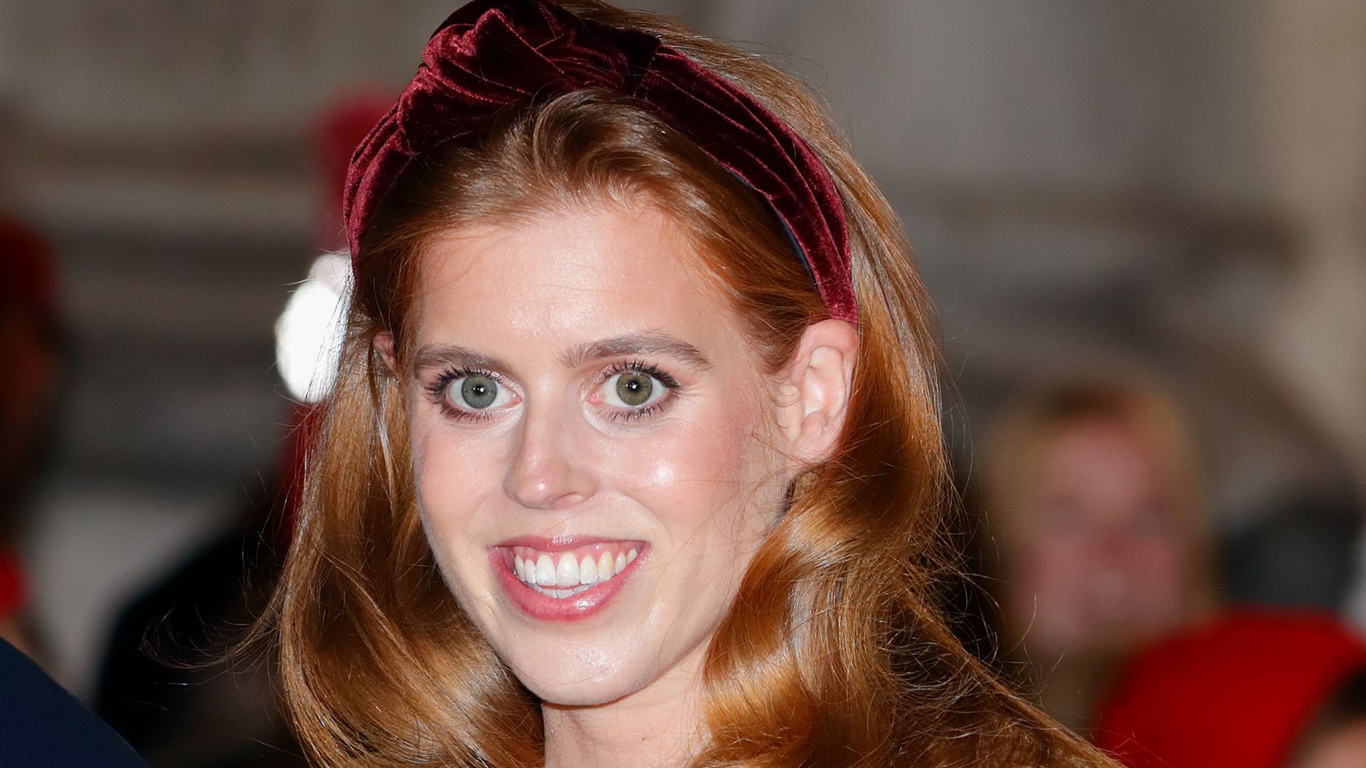 Princess Beatrice smiling in a camel coat