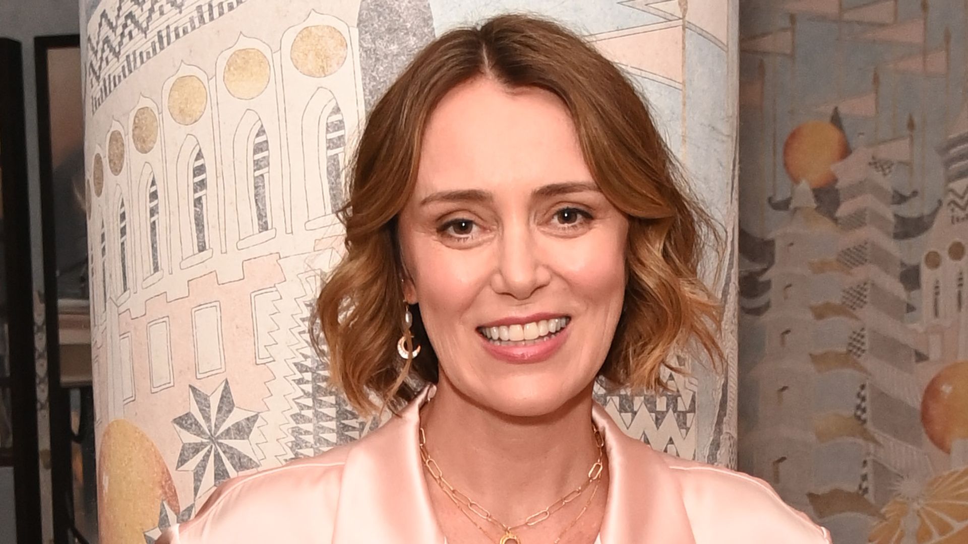 Keeley Hawes with her hands in her pockets in a pinkish outfit
