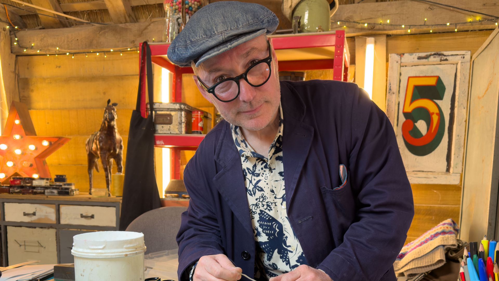 man in workshop at desk working on book