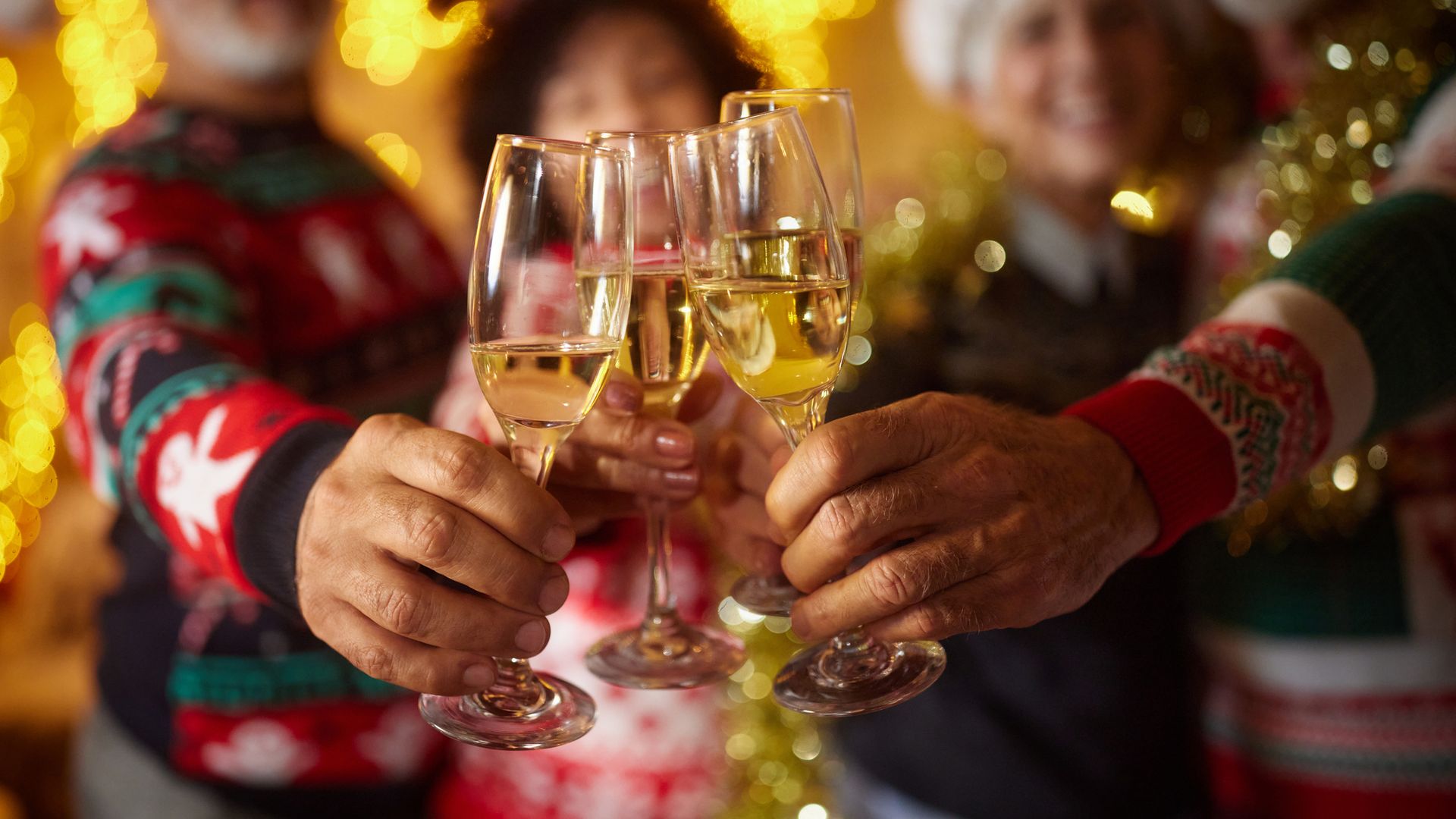 Close up of unrecognizable mature friends toasting with champagne during Christmas party at home.