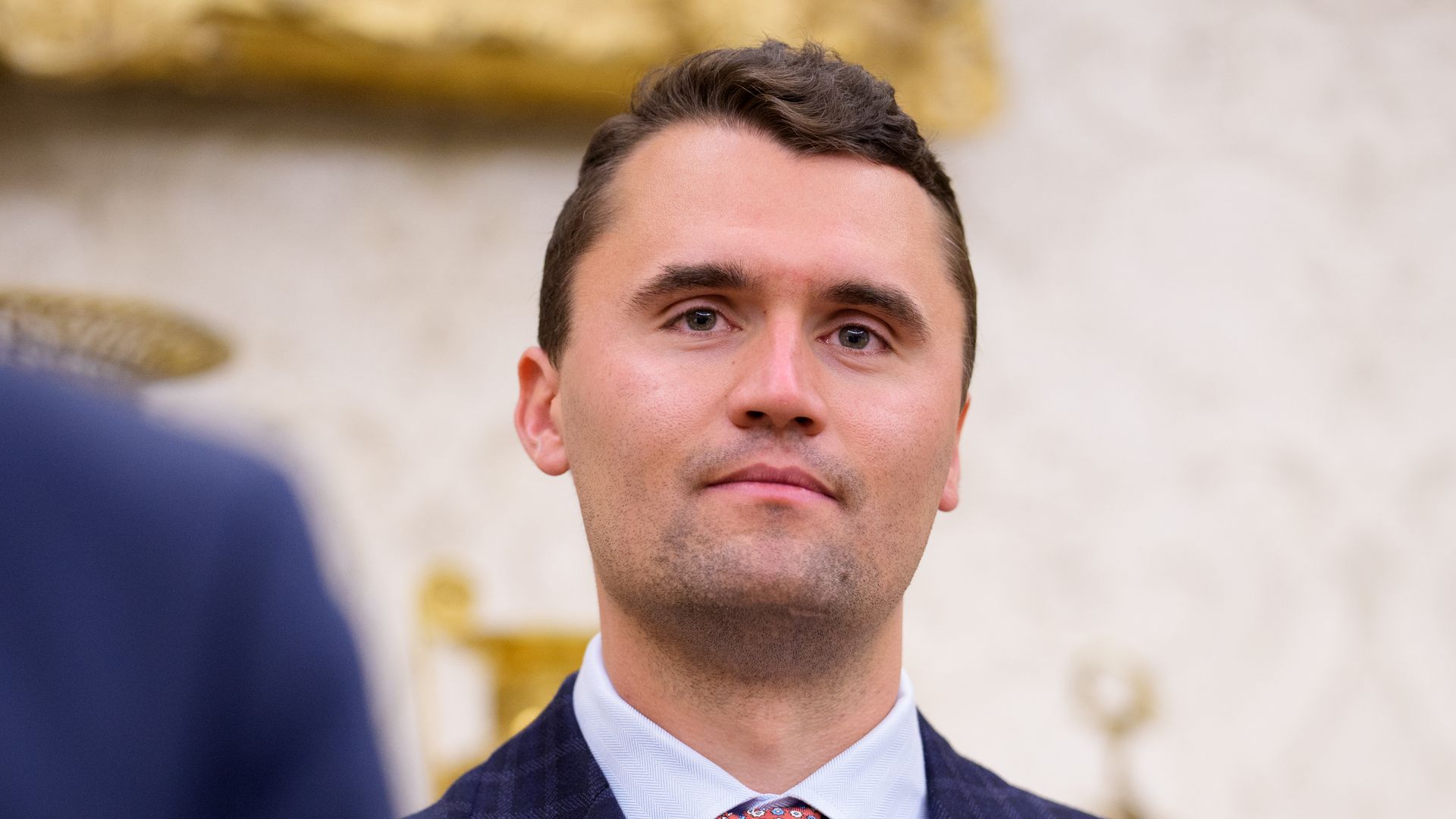 Turning Point USA co-founder Charlie Kirk stands in the back of the room as U.S. President Donald Trump speaks during a swearing in ceremony for interim U.S. Attorney for Washington, D.C. Jeanine Pirro in the Oval Office of the White House on May 28, 2025 in Washington, DC. Trump has announced Pirro, a former Fox News personality, judge, prosecutor, and politician, after losing support in the Senate for his first choice, Ed Martin, over his views on the January 6, 2021 attack on the U.S. Capitol.