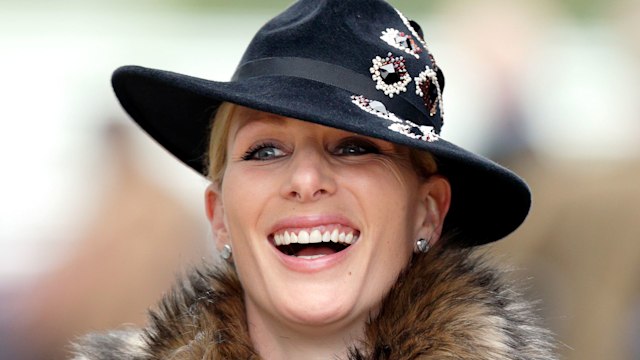 Zara Tindall at Cheltenham Racecourse wearing navy hat and faux fur