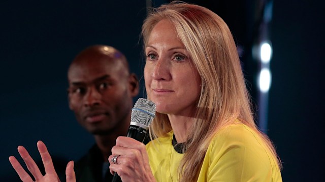 woman speaking into microphone wearing yellow top 