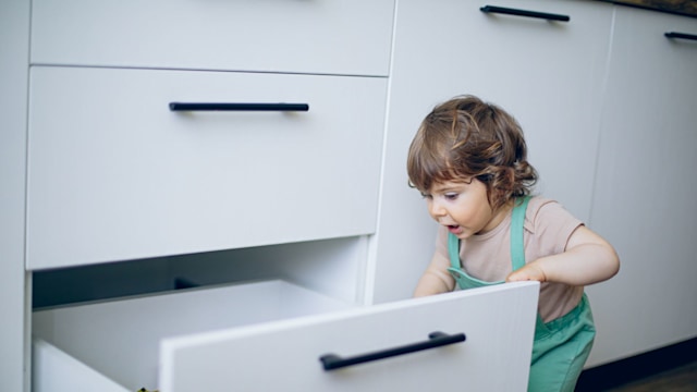 Baby opening kitchen drawer