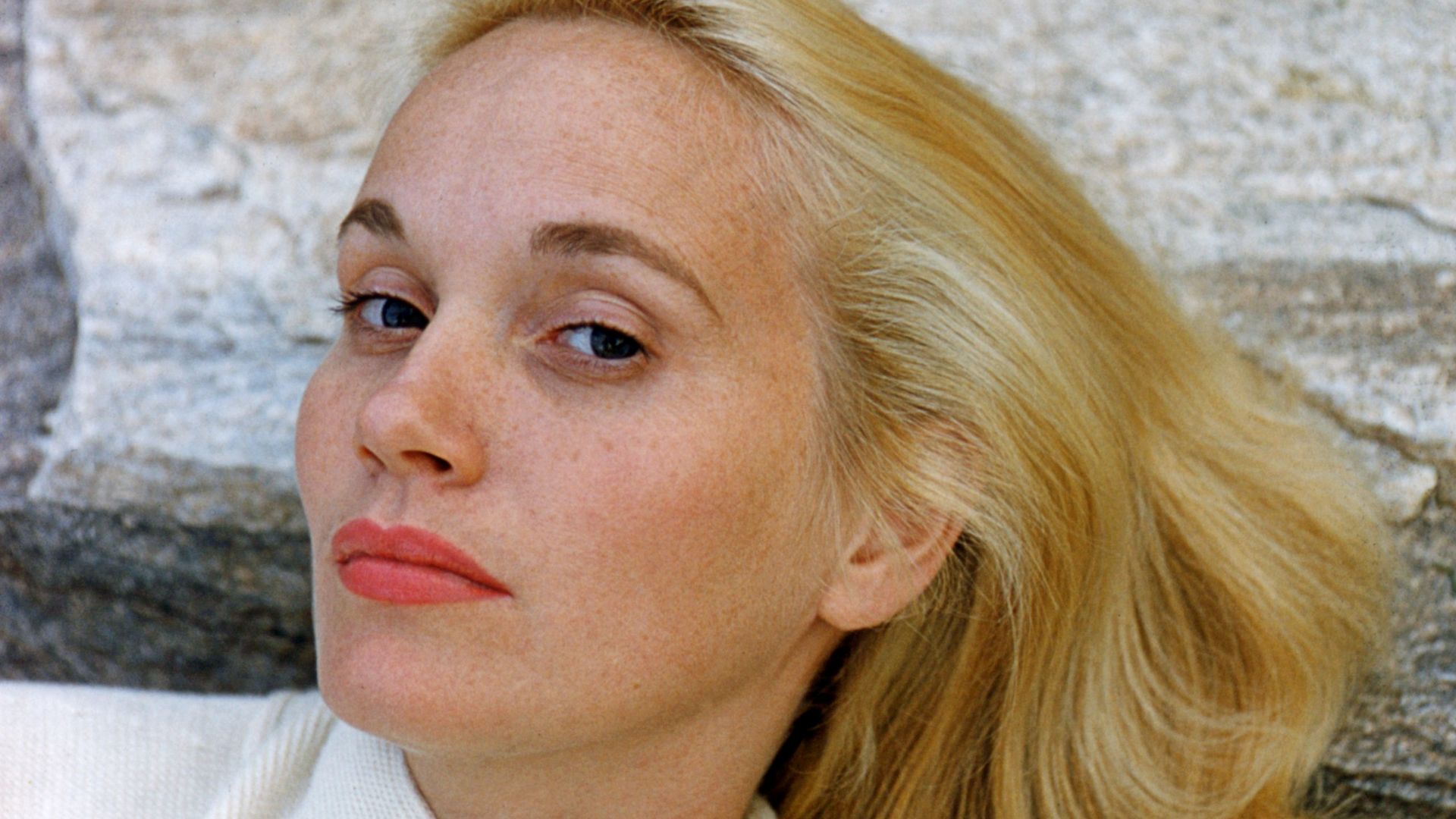 Headshot of Eva Marie Saint, US actress, wearing a white knitted cardigan, posing against a rock, circa 1960