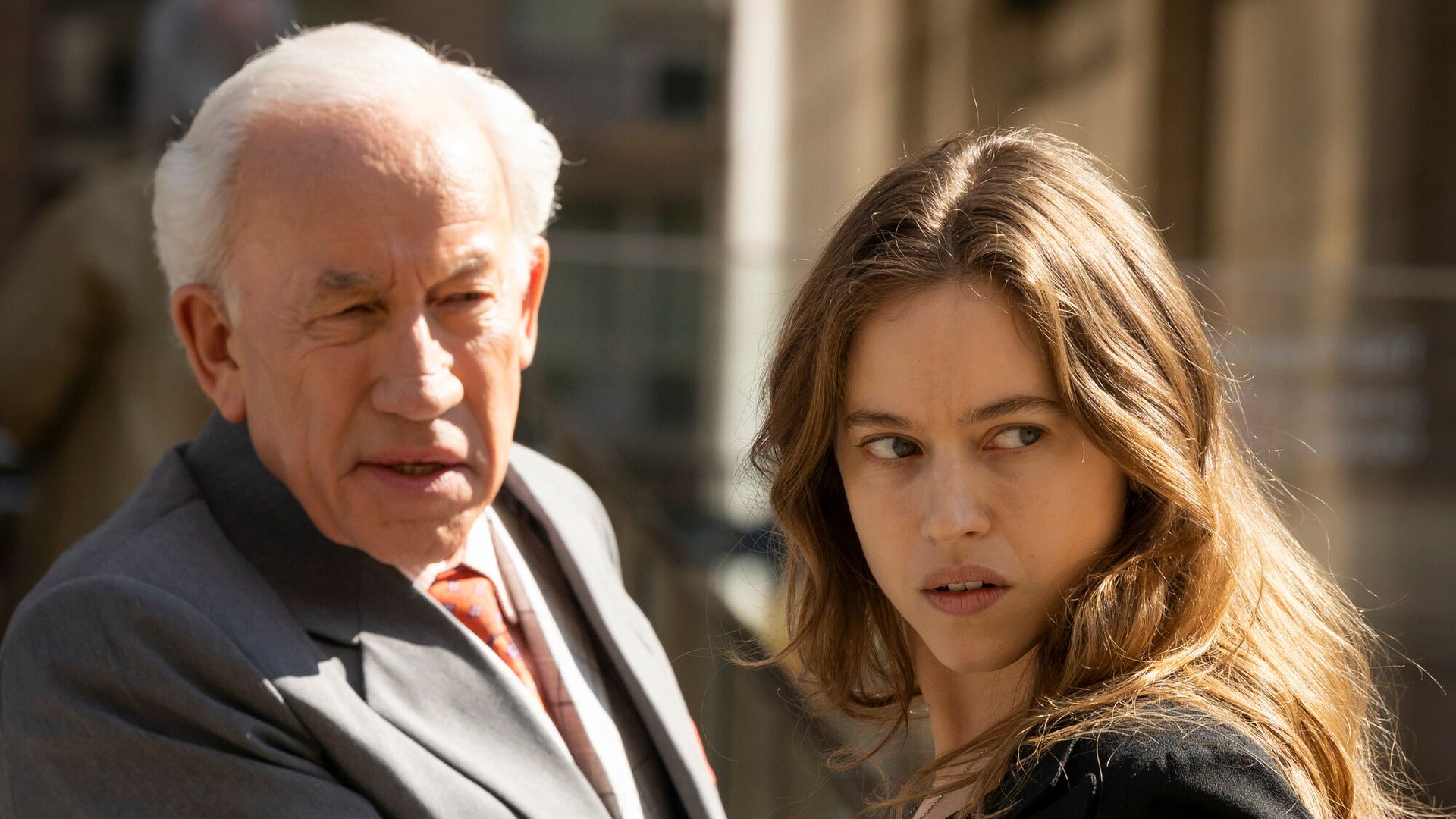 older man and young woman standing in street