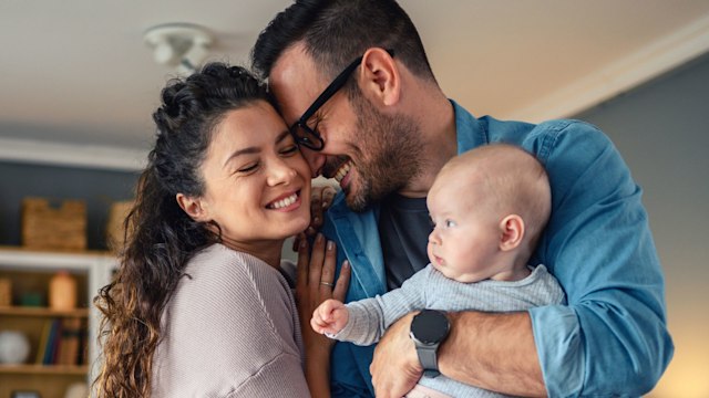 Happy young parents hugging with their baby girl at home