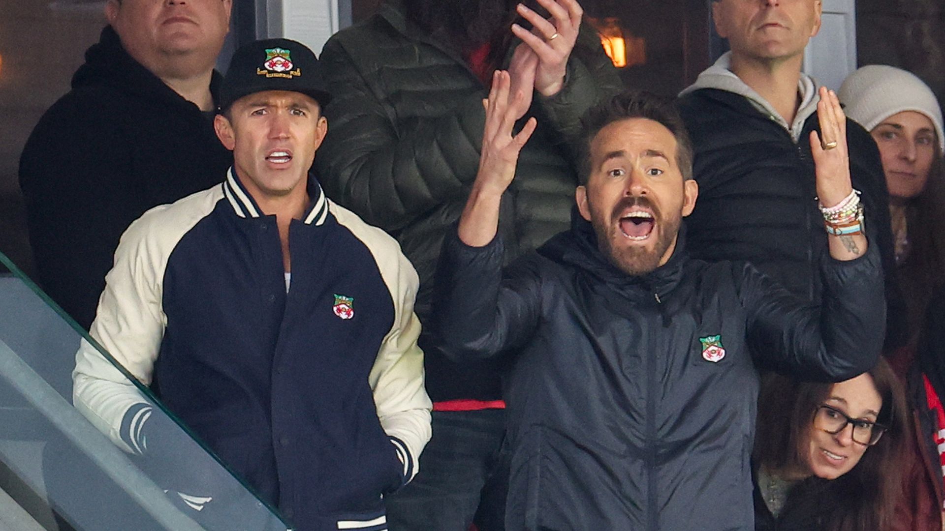 Ryan Reynolds and Rob McElhenney stood reacting to a football game with other fans