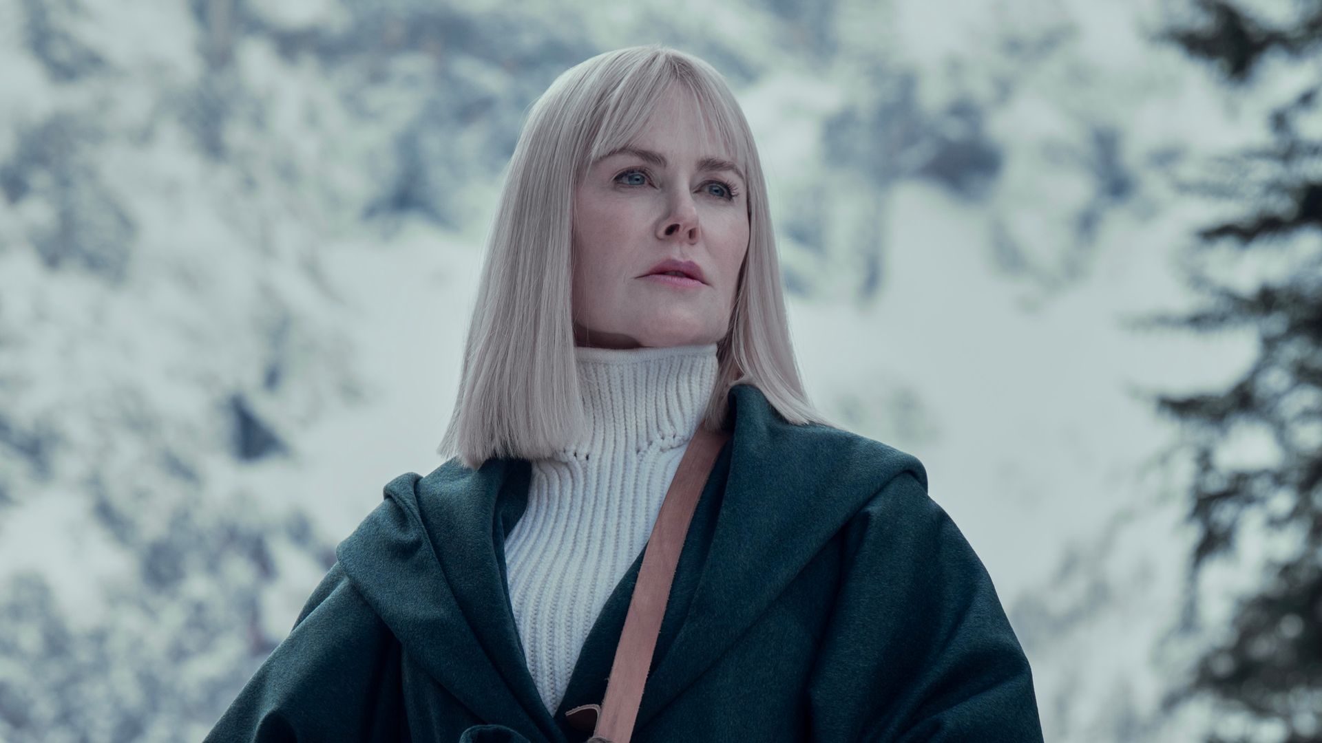 woman with blonde hair standing in front of snowy trees