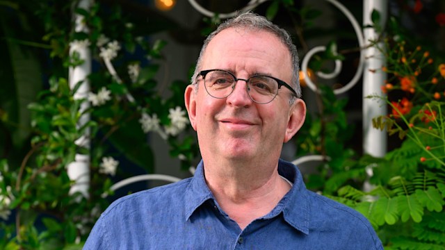 Rev Richard Coles in a blue shirt and cream trousers