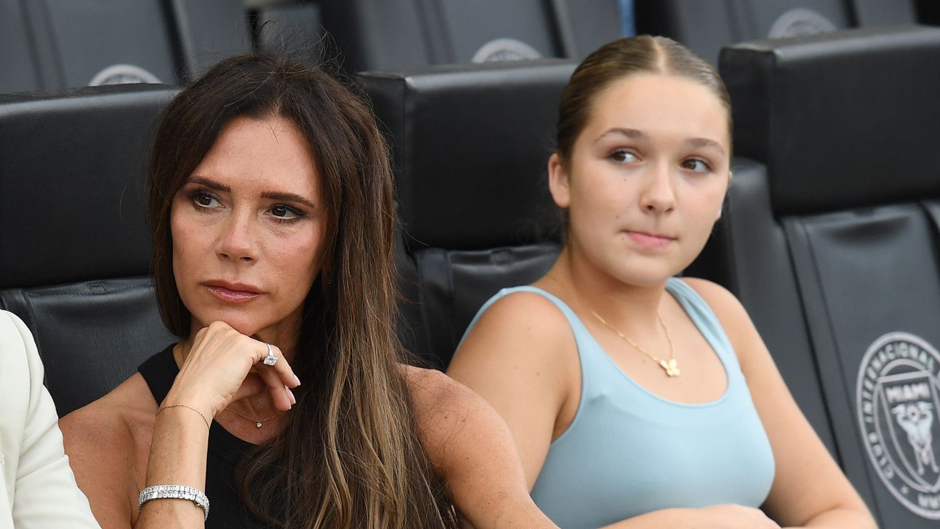 David, Victoria and Harper Beckham sitting in a sports stadium