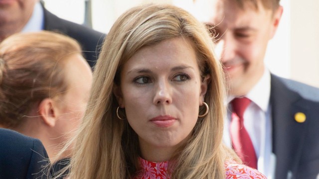 Carrie Johnson with a straight face in a pink floral dress