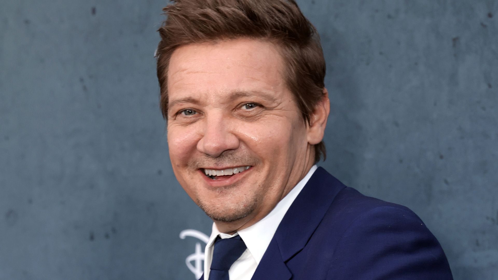 Jeremy Renner smiling for a photo on a red carpet