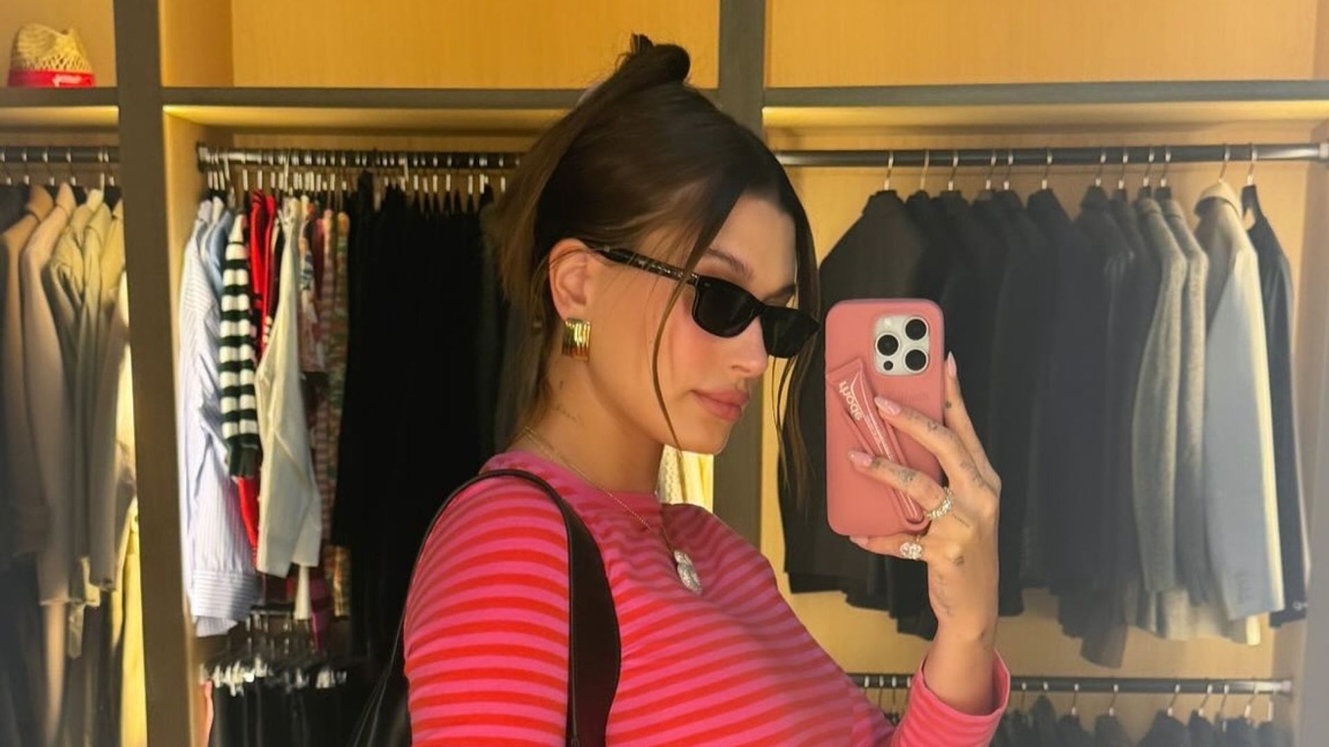 Hailey Bieber wearing a stripey pink top and black trousers