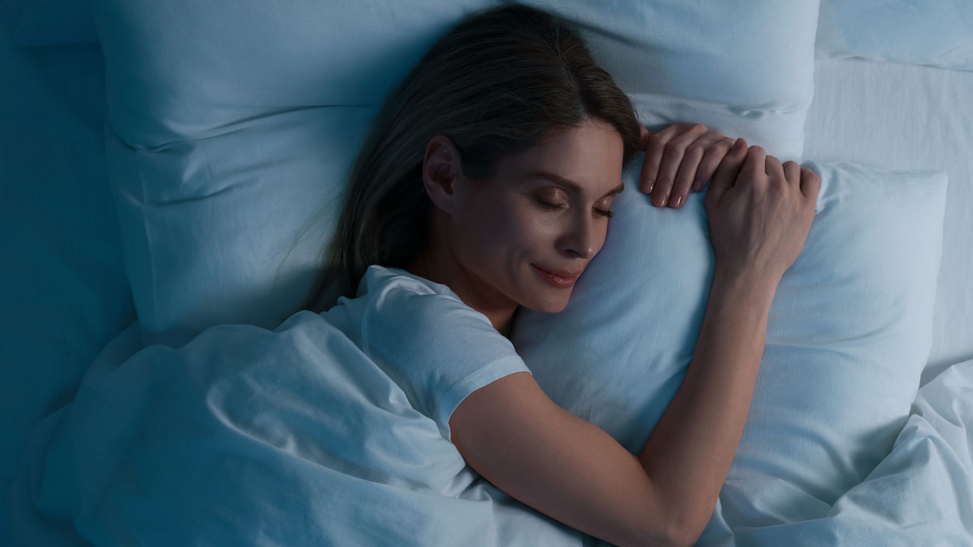 woman sleeping  in bed at night hugging pillow