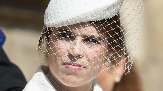 Close-up of Princess Eugenie wearing a white textured hat with a birdcage veil and a soft cream trench, with minimal makeup and neatly styled hair for Easter Sunday.