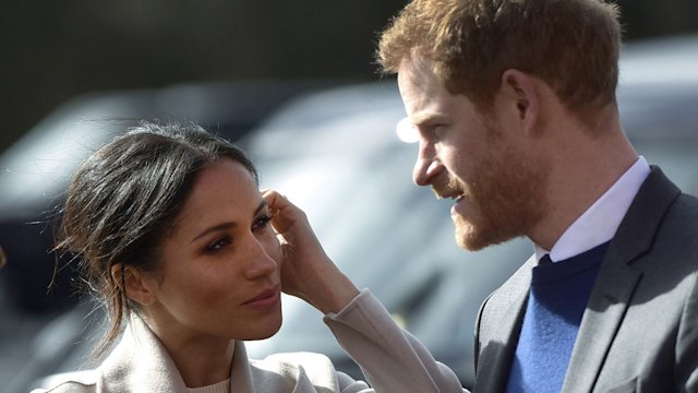 Meghan Markle fixing her hair and looking at Prince Harry