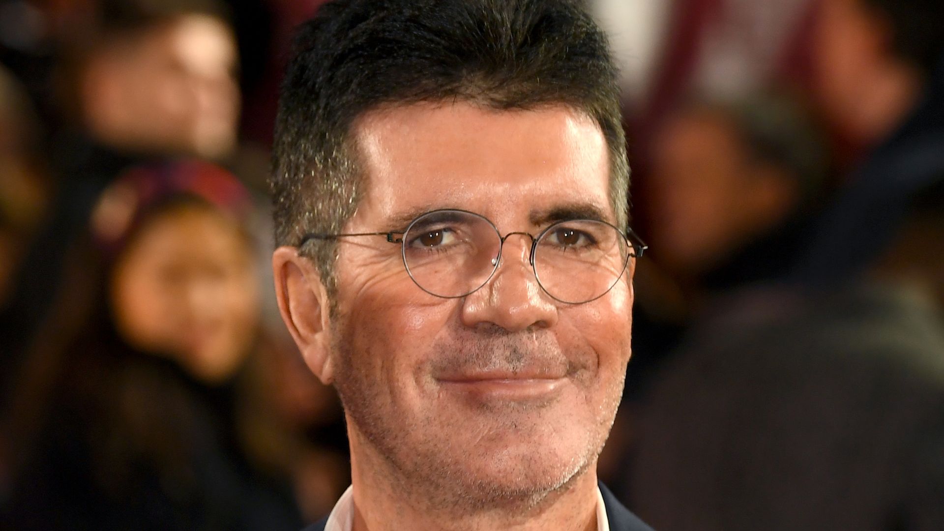 Simon Cowell in a suit and an open shirt with glasses