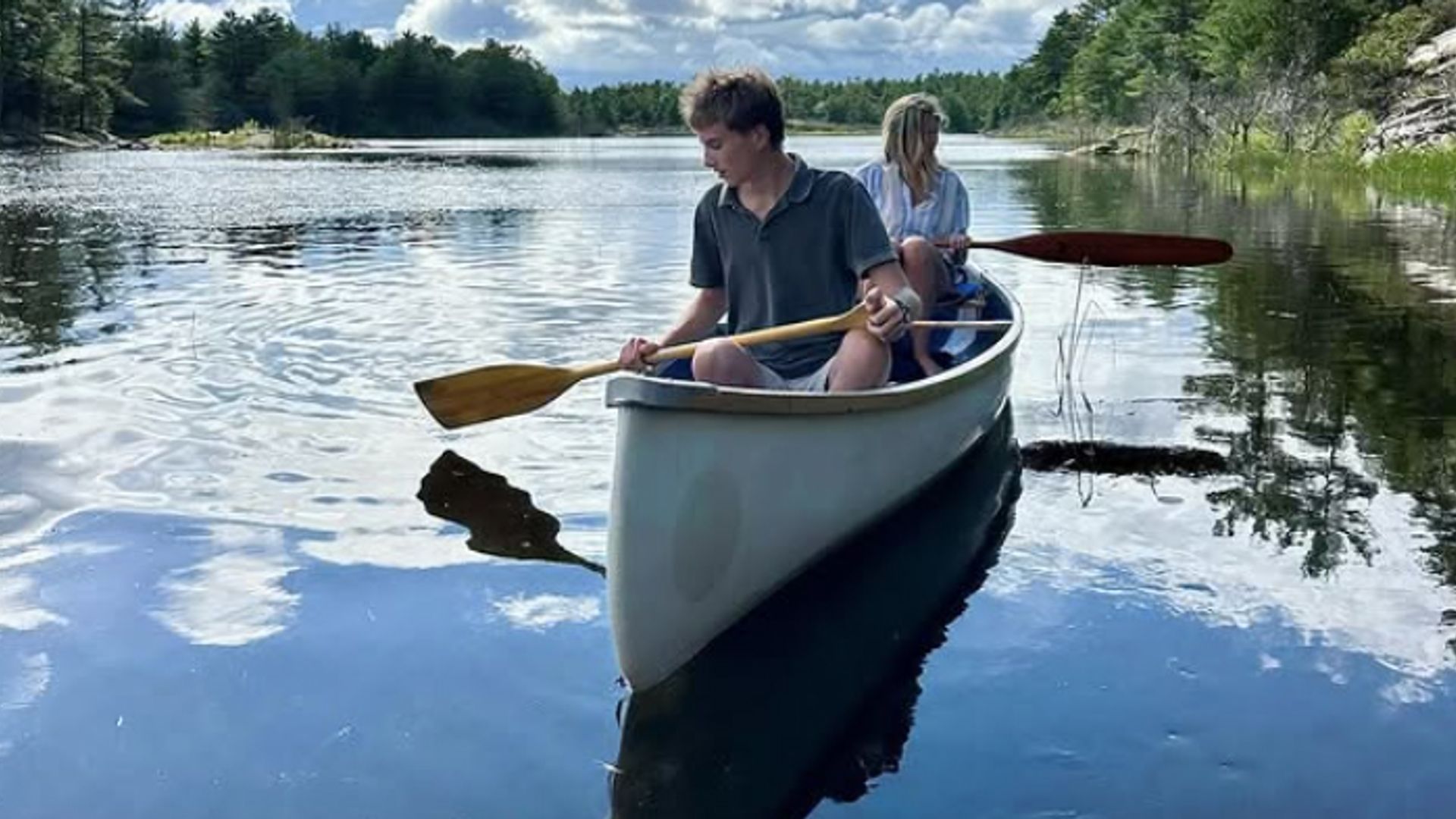 Un adolescent et sa mère dans un bateau avec des pagaies