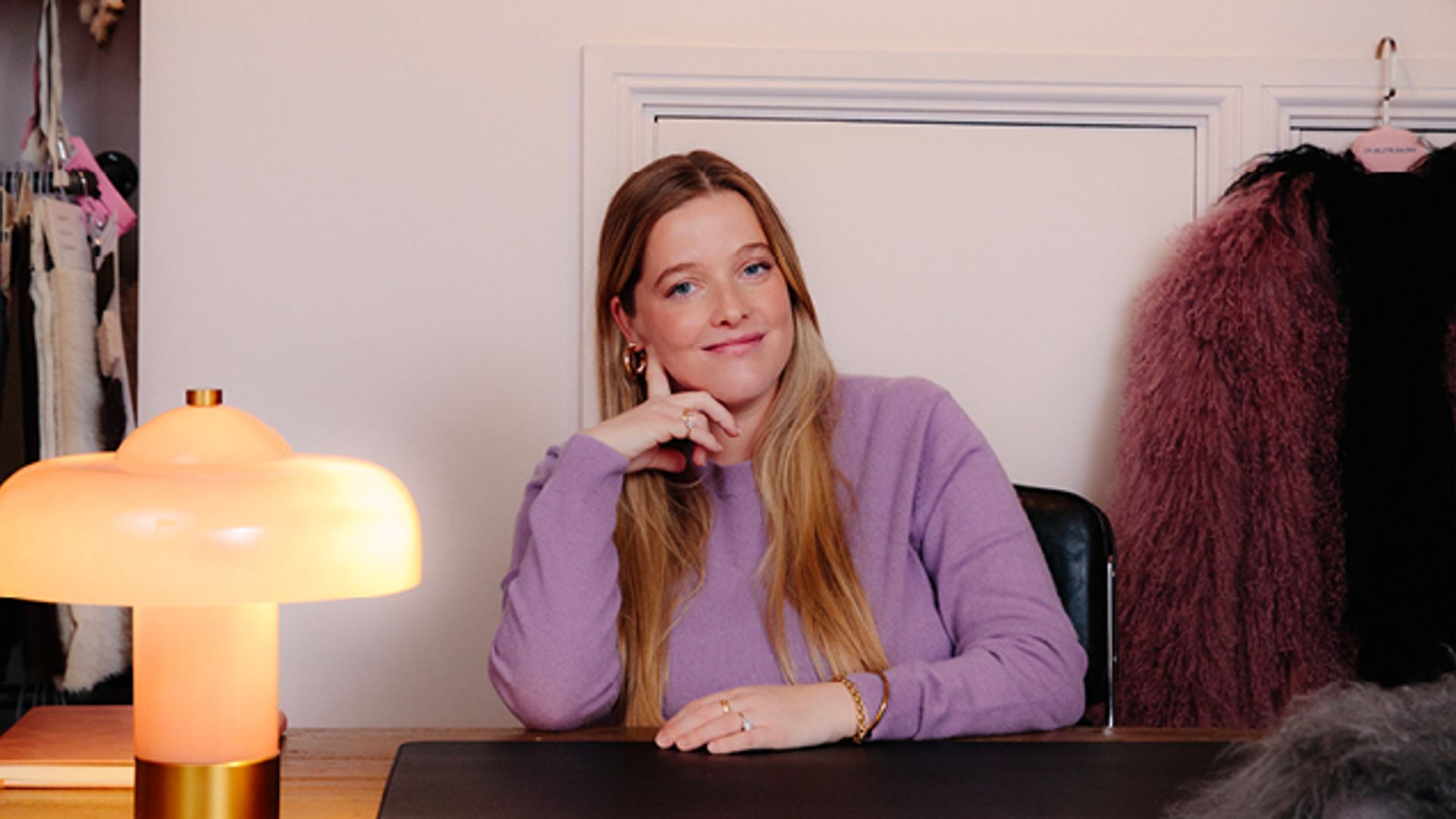 woman in a purple jumper sitting at her desk