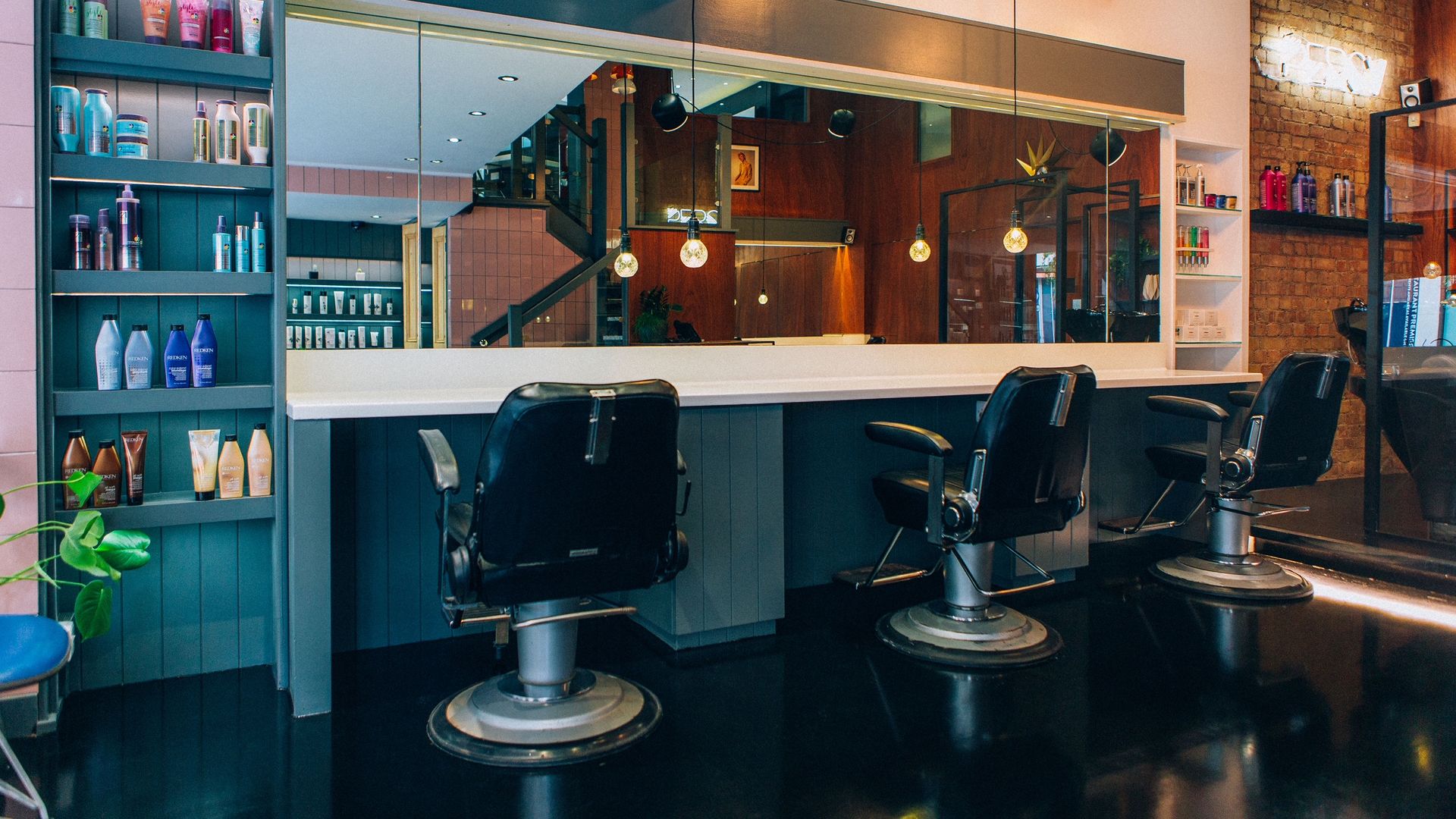 Black salon chairs and large wall mirror at Percy & Reed hair salon