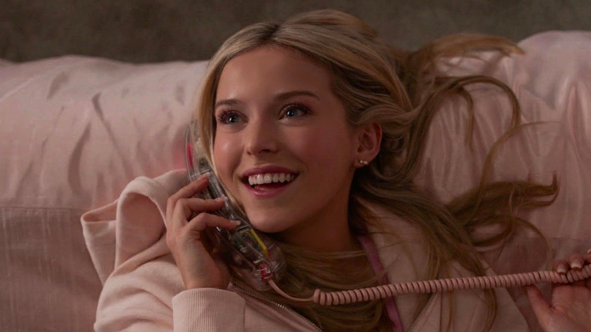 young woman lying on bed on phone