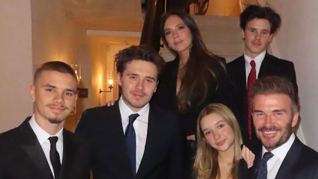David and Victoria Beckham with their four children standing on the stairs in their home smiling for a photo