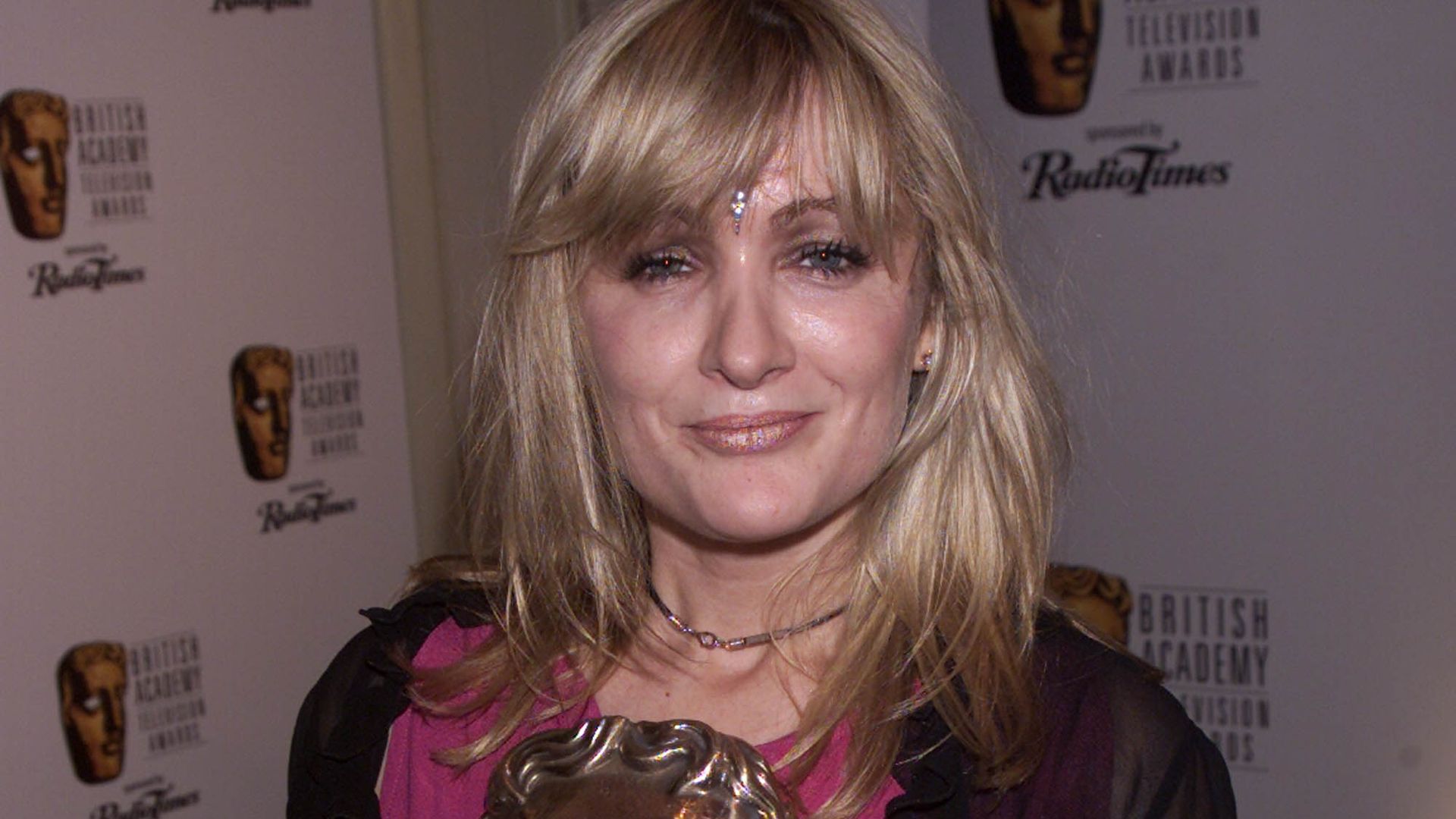 Caroline Ahern smiling holding a BAFTA