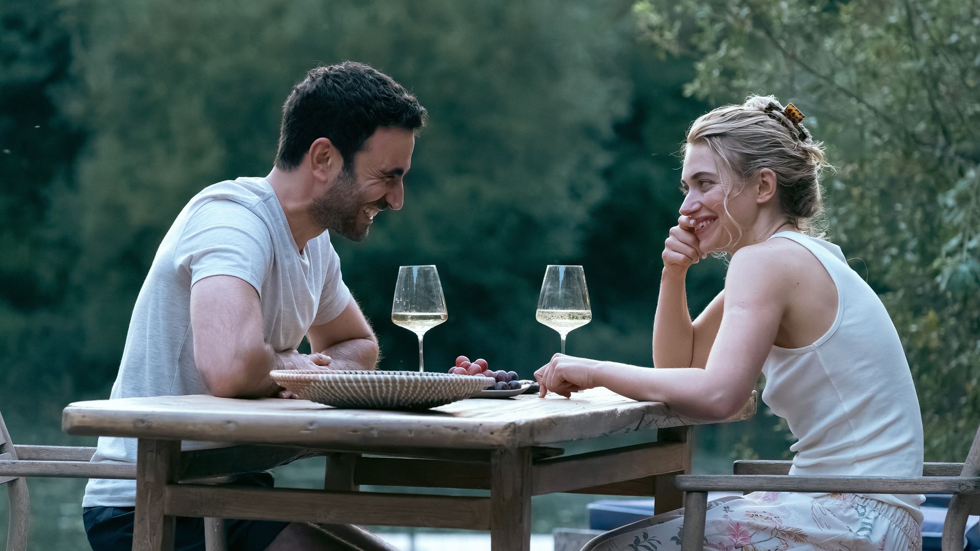 Brett Goldstein and Imogen Poots sitting across the table from each other drinking white wine in All for You