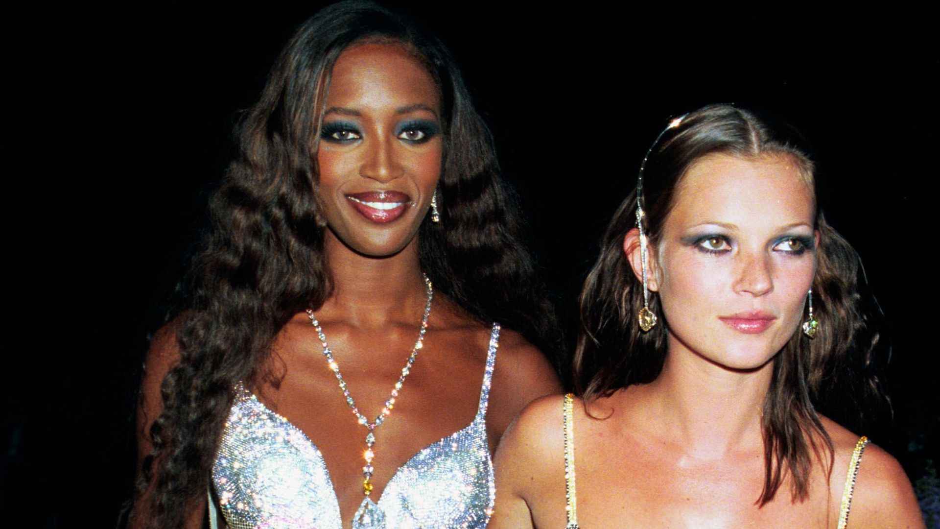 Models Naomi Campbell and Kate Moss wearing silver dresses