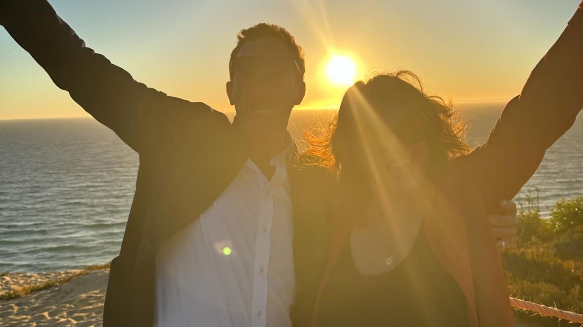 Princess Eugenie and Jack Brooksbank posing in front of a sun setting