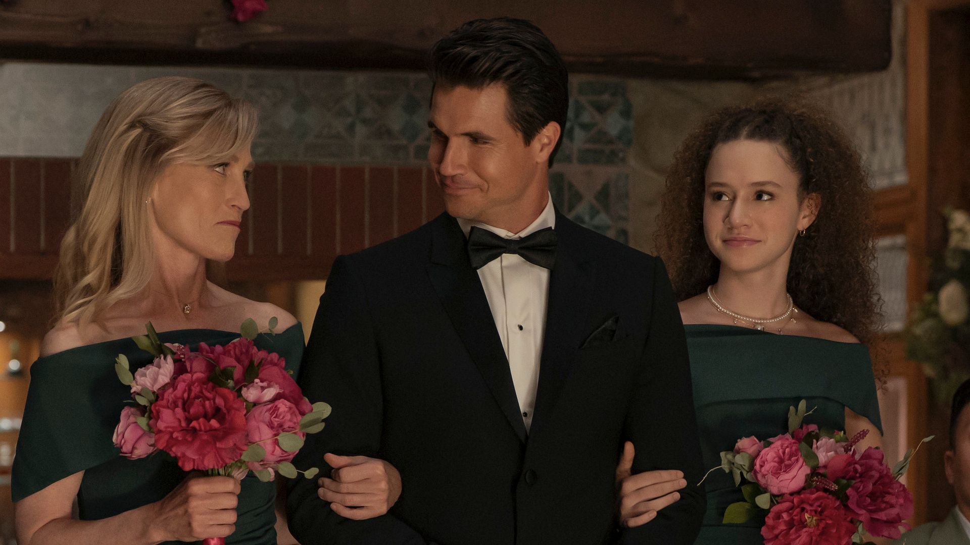 Robbie Amell with two girls on his arms in a scene from Upload