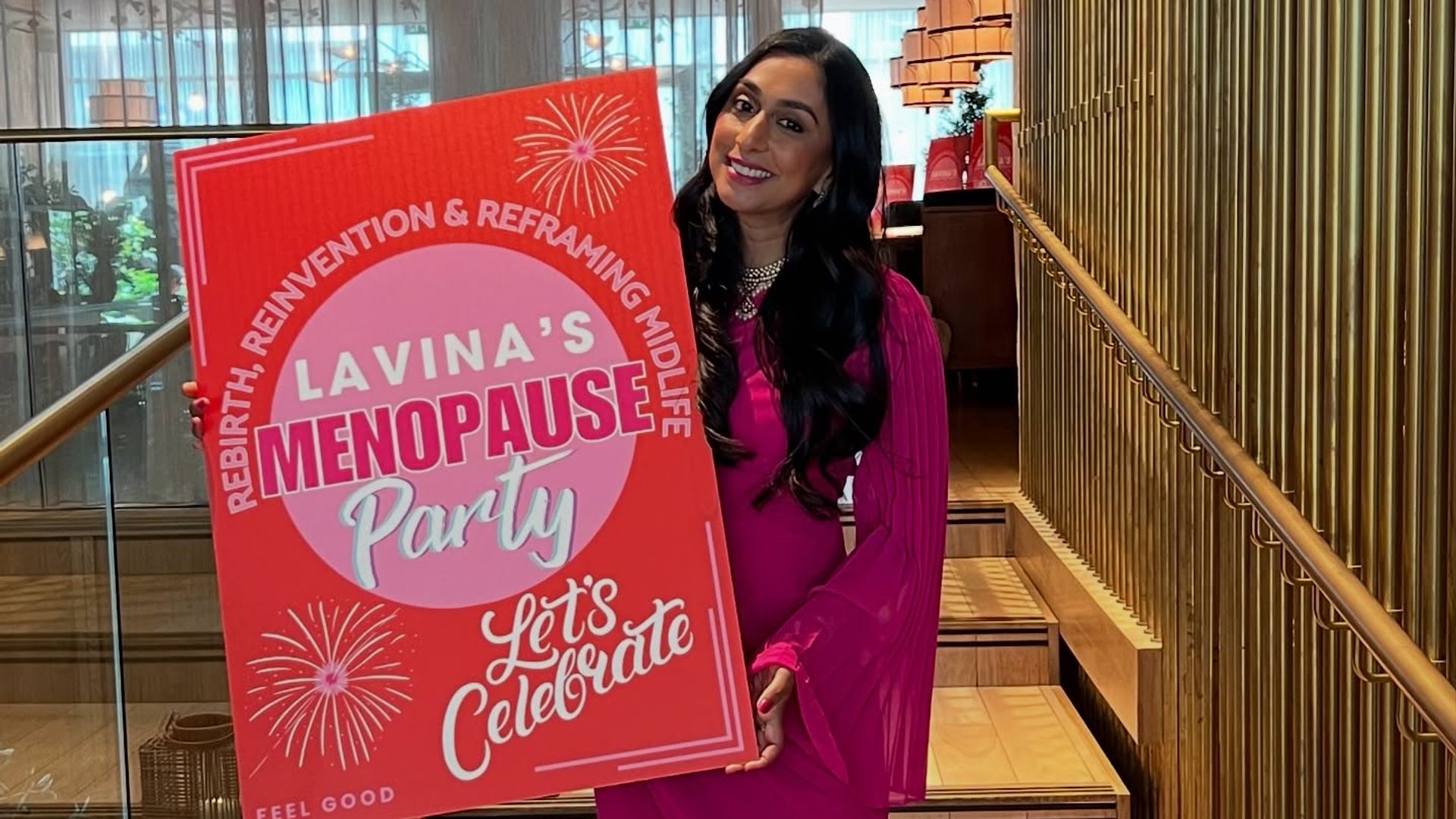 Woman in a pink dress holding a sign about a menopause party