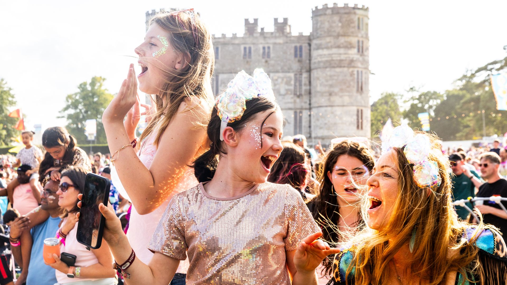 Crowd of old and young people having fun in a field with a castle in the background