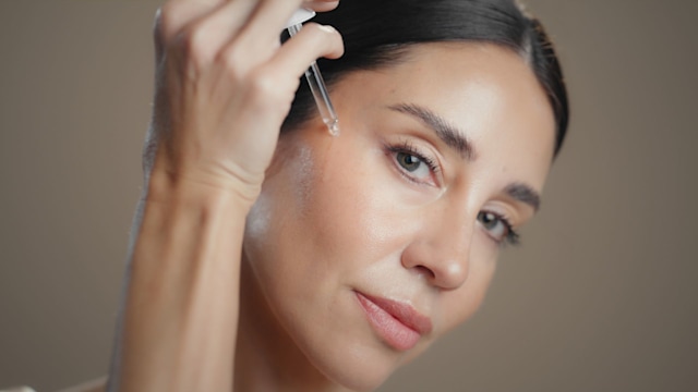 woman applying serum to her face