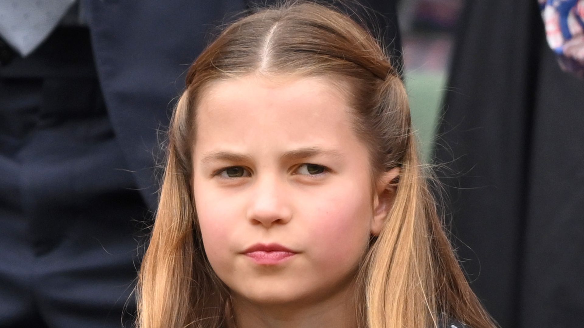 Princess Charlotte frowning in navy polka dot dress