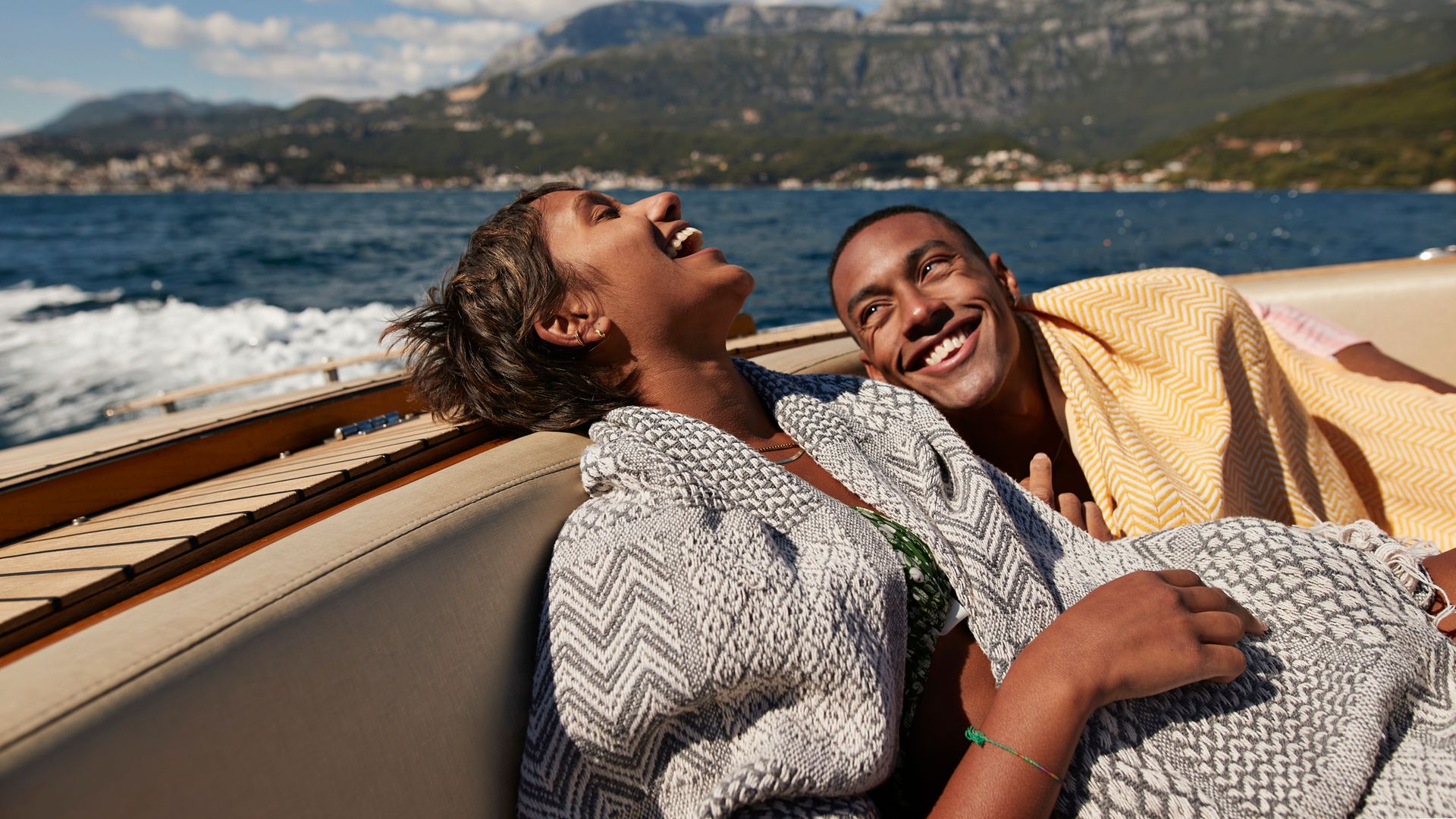 Young man and woman laughing in speedboat enjoying summer on sunny day