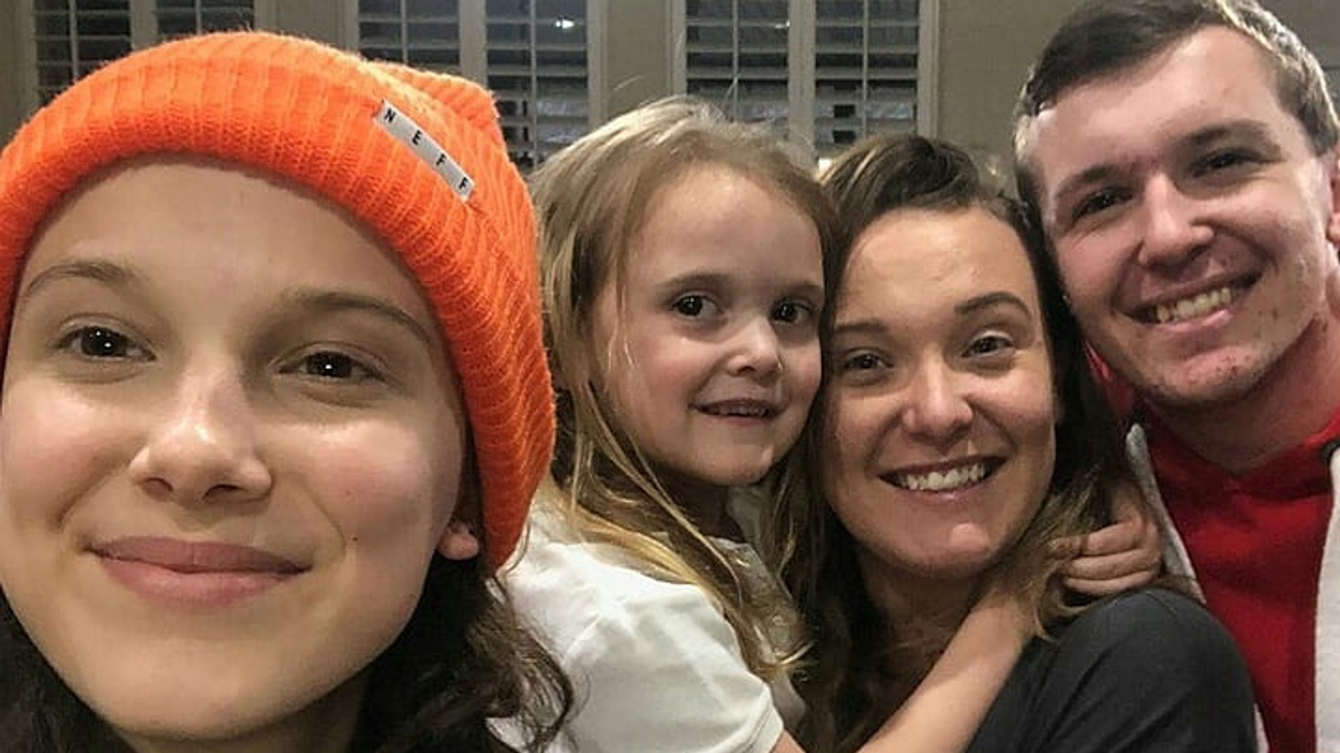 Millie Bobby Brown wearing a beanie hat and taking a selfie with her three siblings
