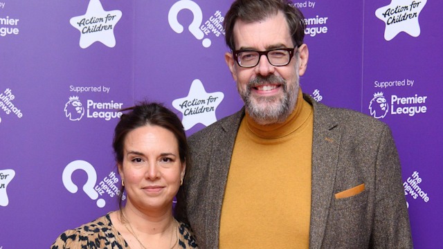 Richard Osman in a yellow jumper and a blazer with his wife Ingrid Oliver