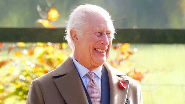 King Charles smiling in a brown coat