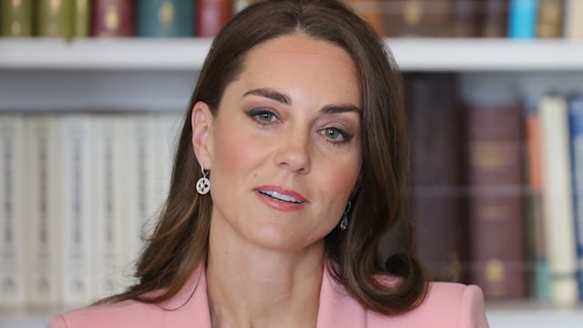 Kate Middleton listens in front of bookcase 