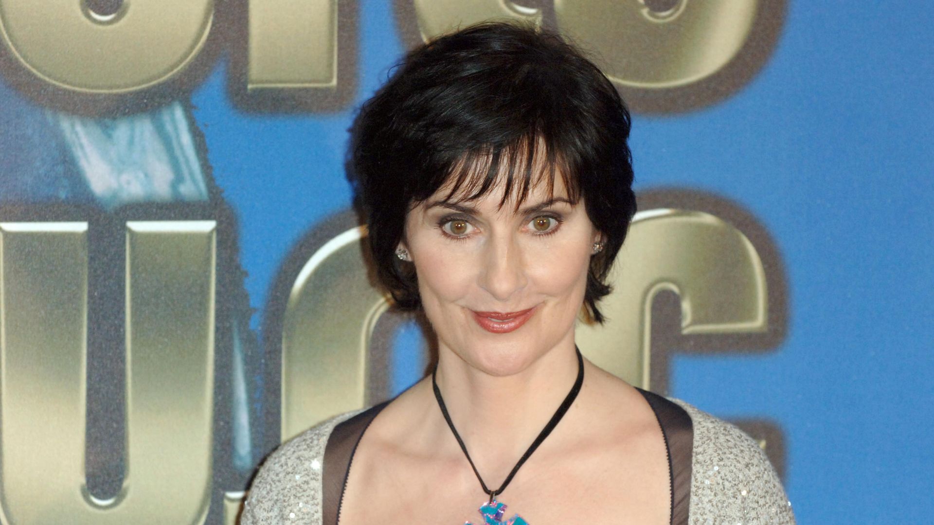 woman with dark short hair with blue cross necklace