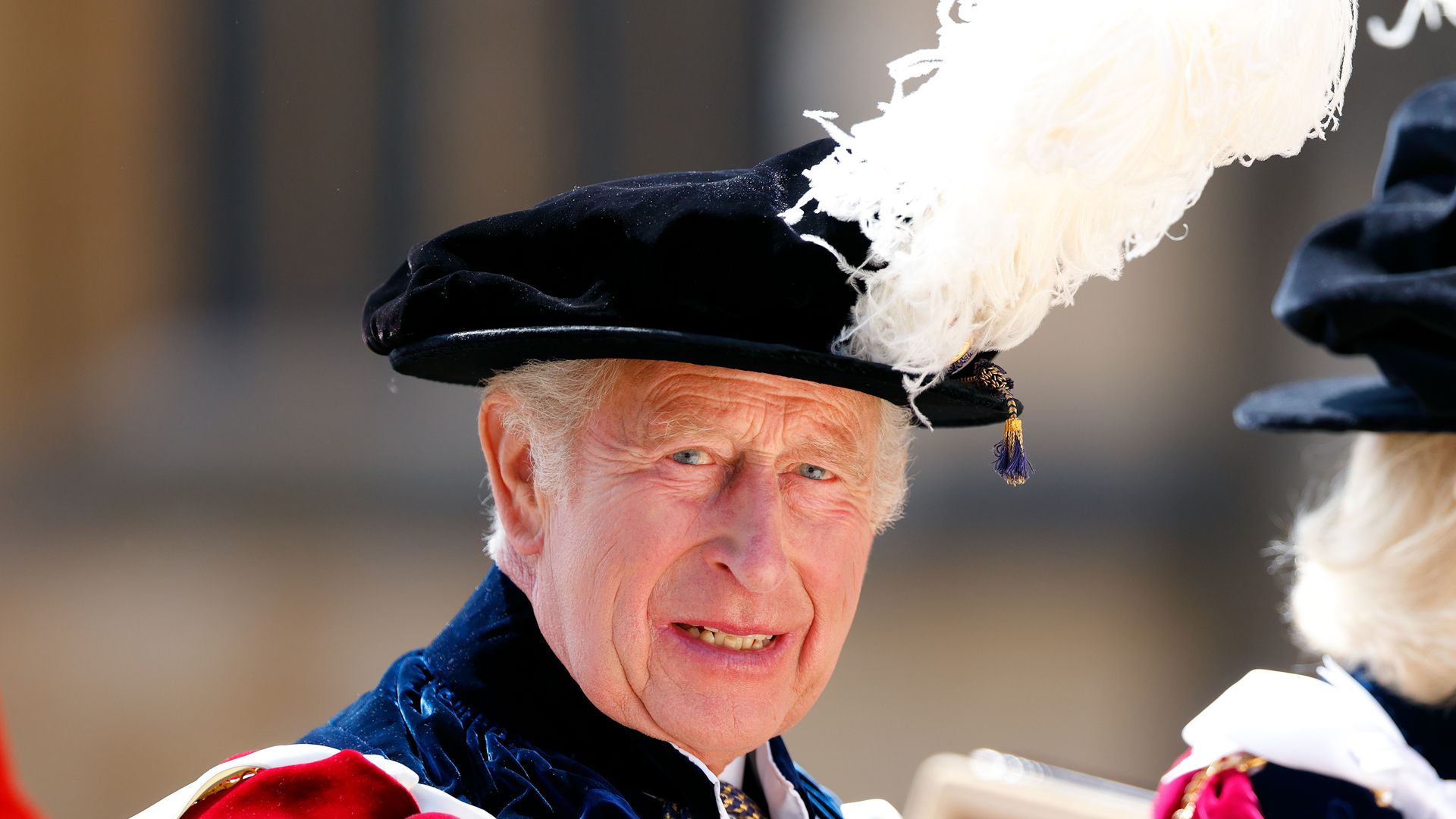 King Charles in a feather plume hat and red robes in a carriage