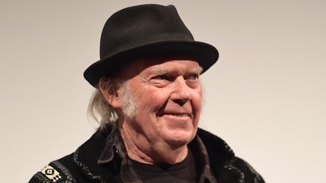 Neil Young in a black outfit and hat