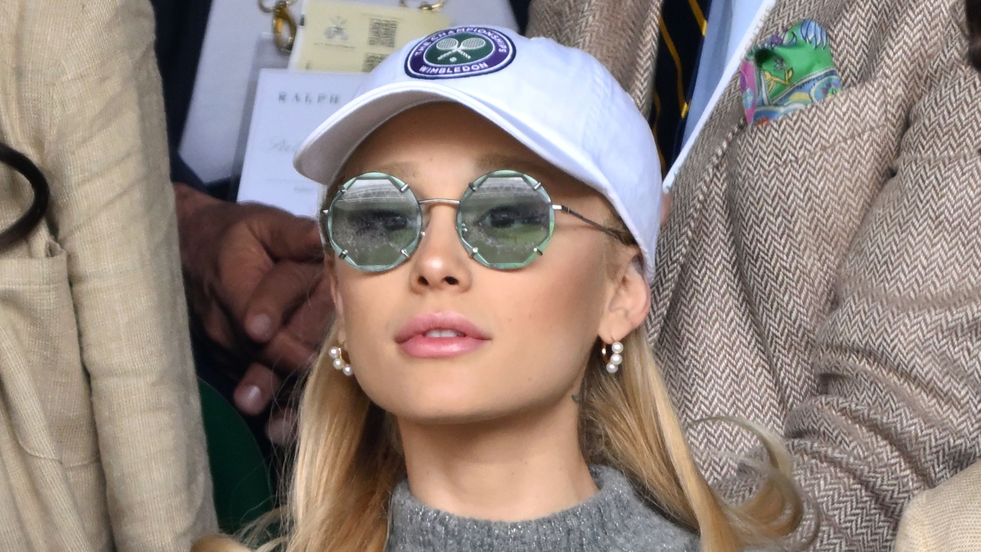 Ariana Granda in a grey jumper and a cap